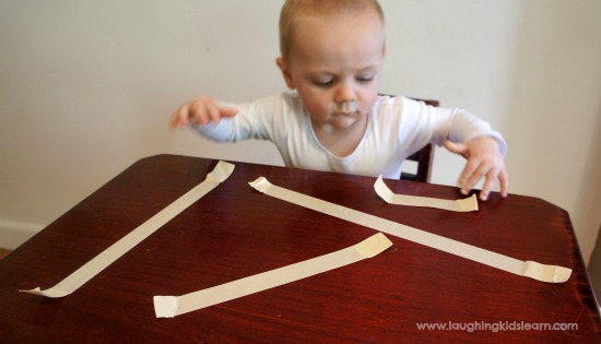 baby play game with sticky tape and pulling it off a table. Great for fine motor development.