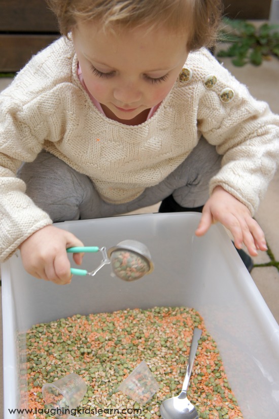 scooping and pouring beans in a sensory bin