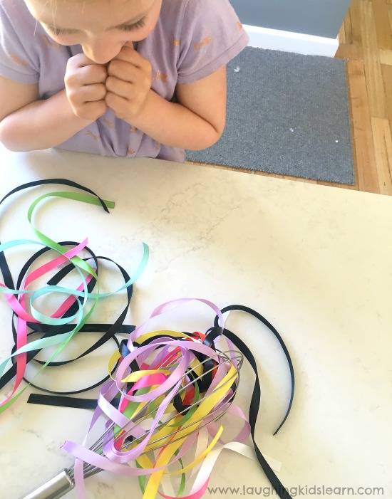 Ribbon and whisk fine motor activity for kids is fun and easy to set up. #finemotor #finemotorskills #ribbons #lovetoplay #simpleplayideasforkids #indooractivities #babyplay #babyplayideas #homeschooling #homeschool #lovetolearn #preschool #playgroup #playtime #mothersgroup
