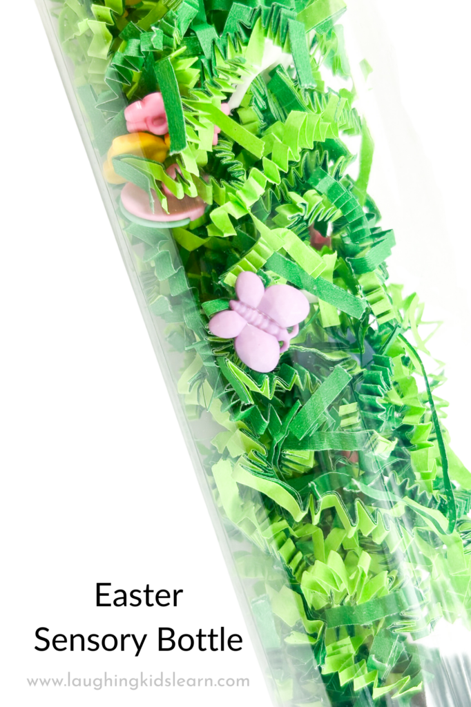 Easter-themed sensory bottle with green paper and charms. DIY Easter Sensory Bottle